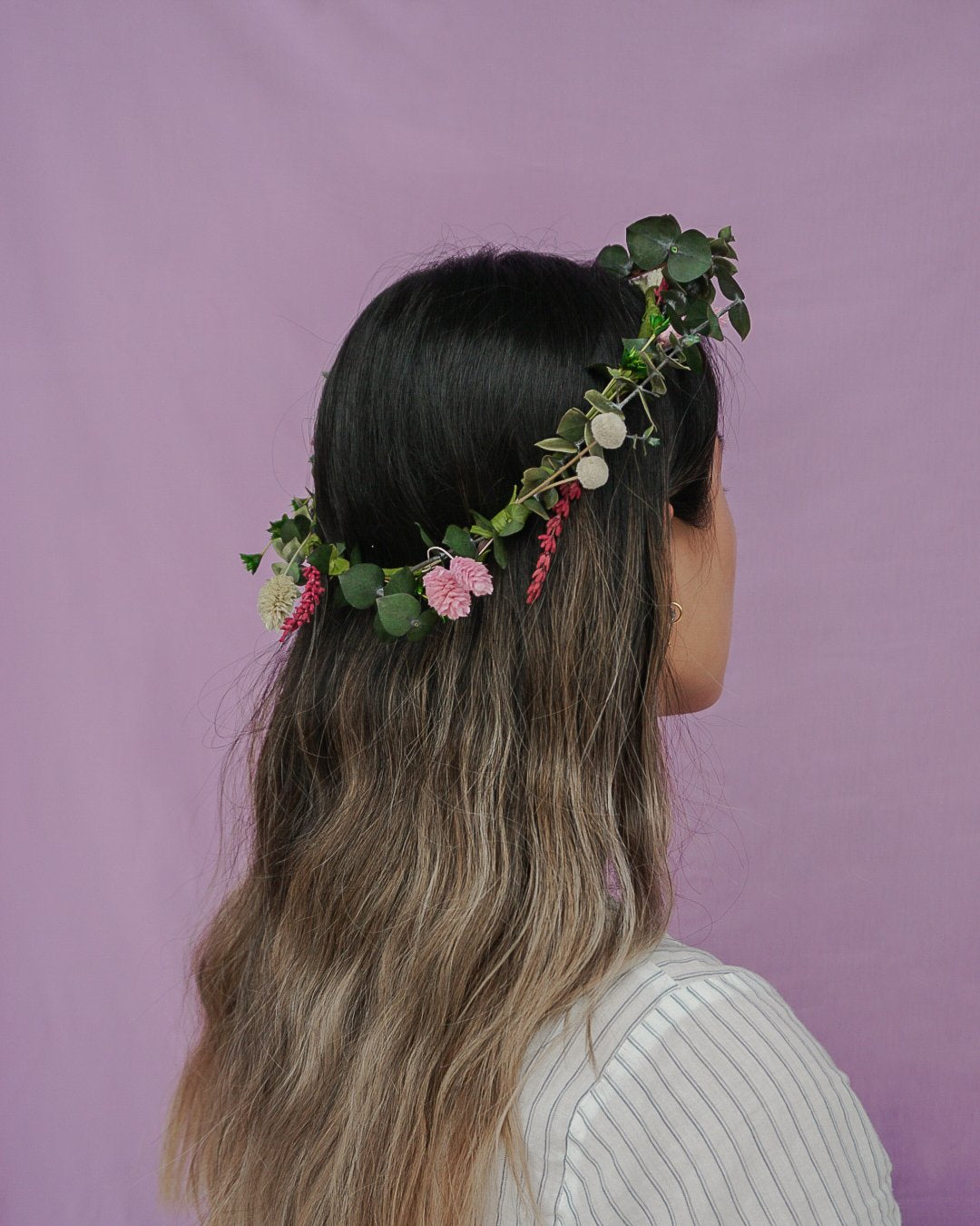 En ung kvinde bærer en blomsterkrans af langtidsholdbare blomster i det løse hår.
