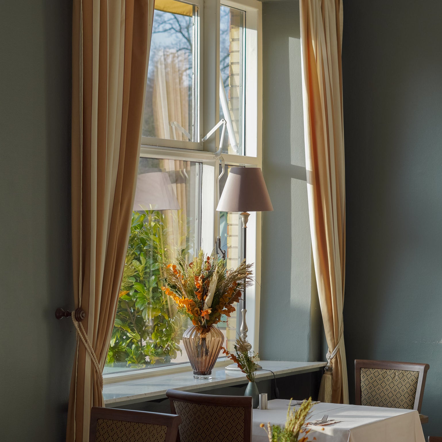 I hotellets spisesal står langtidsholdbare blomsterbuketter i forskellige størrelser på borde og vindueskarme.