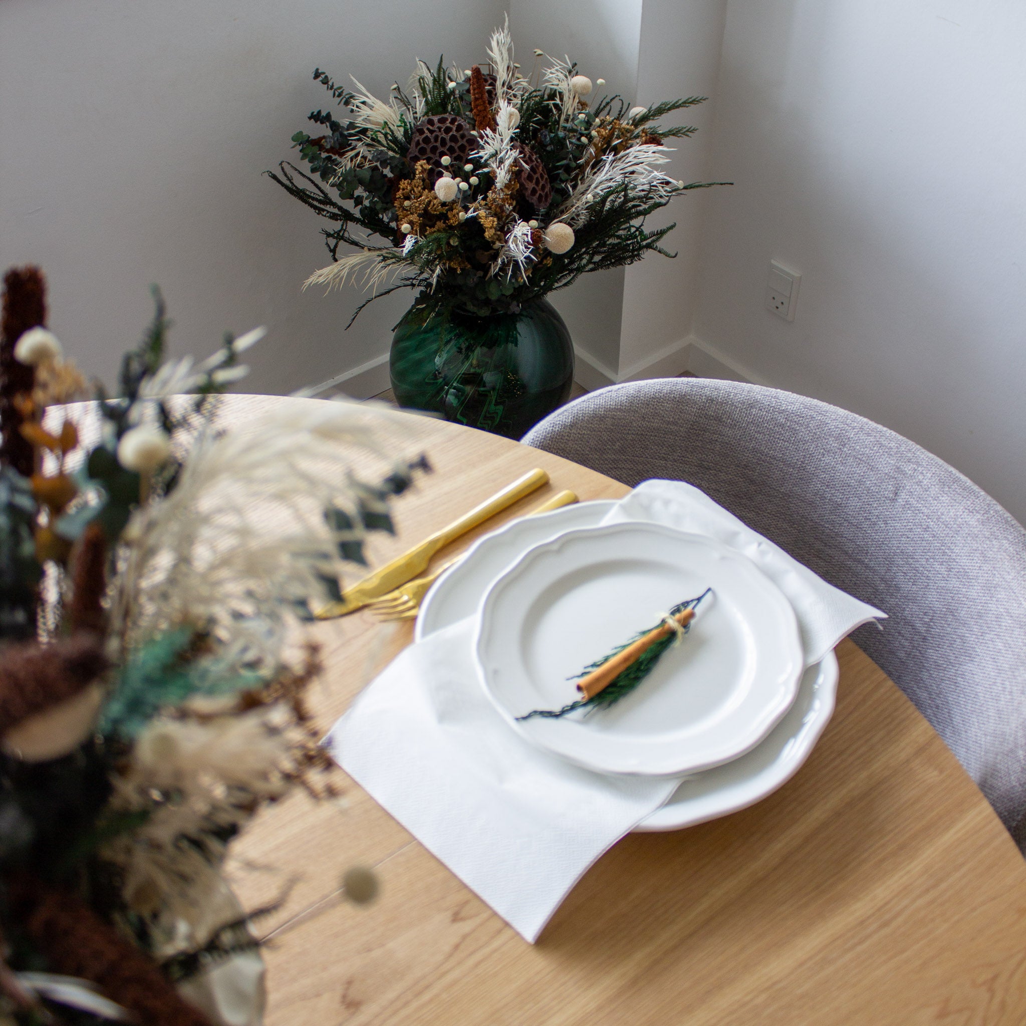 Et julepyntet bord med langtidsholdbare buketter i jordfarver placeret på og ved siden af bordet.