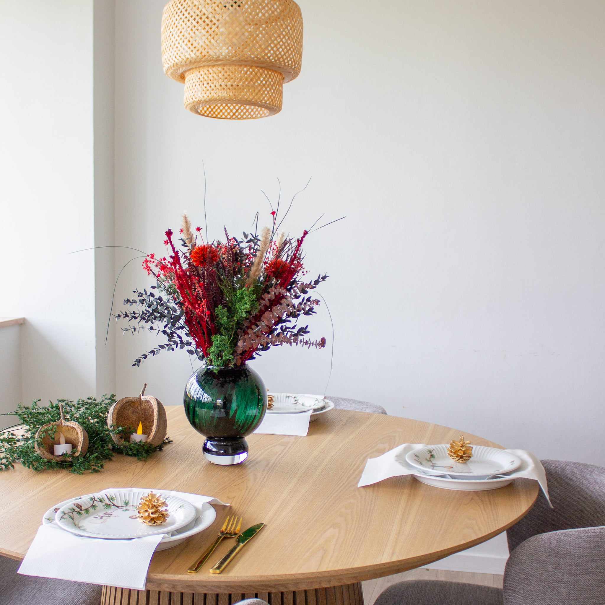 Et minimalistisk dækket julebord med en rød buket som midtpunkt.