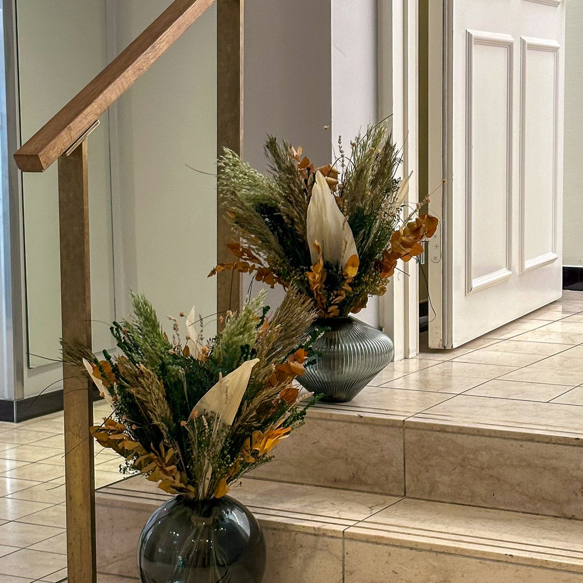 På trappelandingene på hotellet står to blomsterbuketter i efterårsfarver.