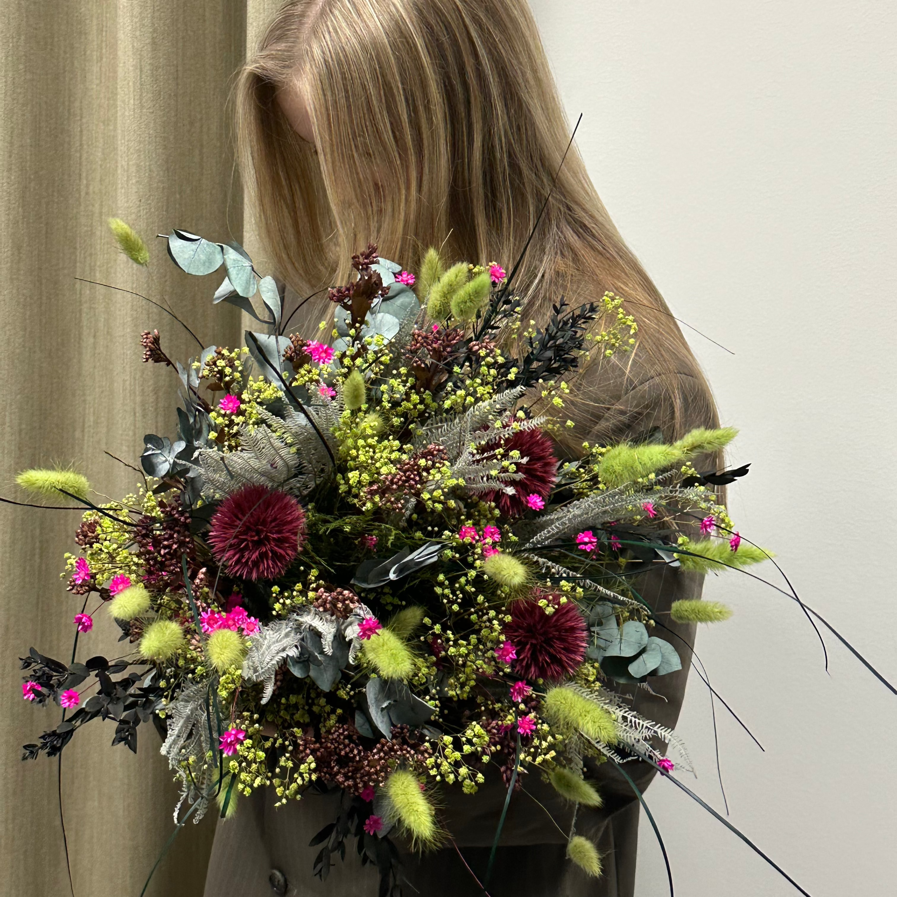 En pige holder en grøn-pink buket.