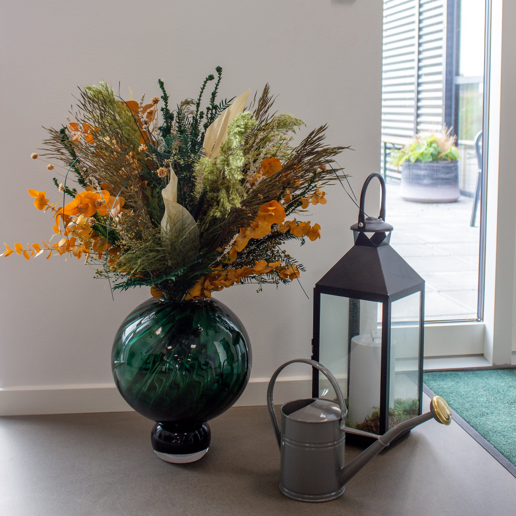 En stor efterÄrsinspireret blomsterbuket stÄr ved siden af anden dekoration pÄ gulvet i receptionen hos Living Flower-kontoret.