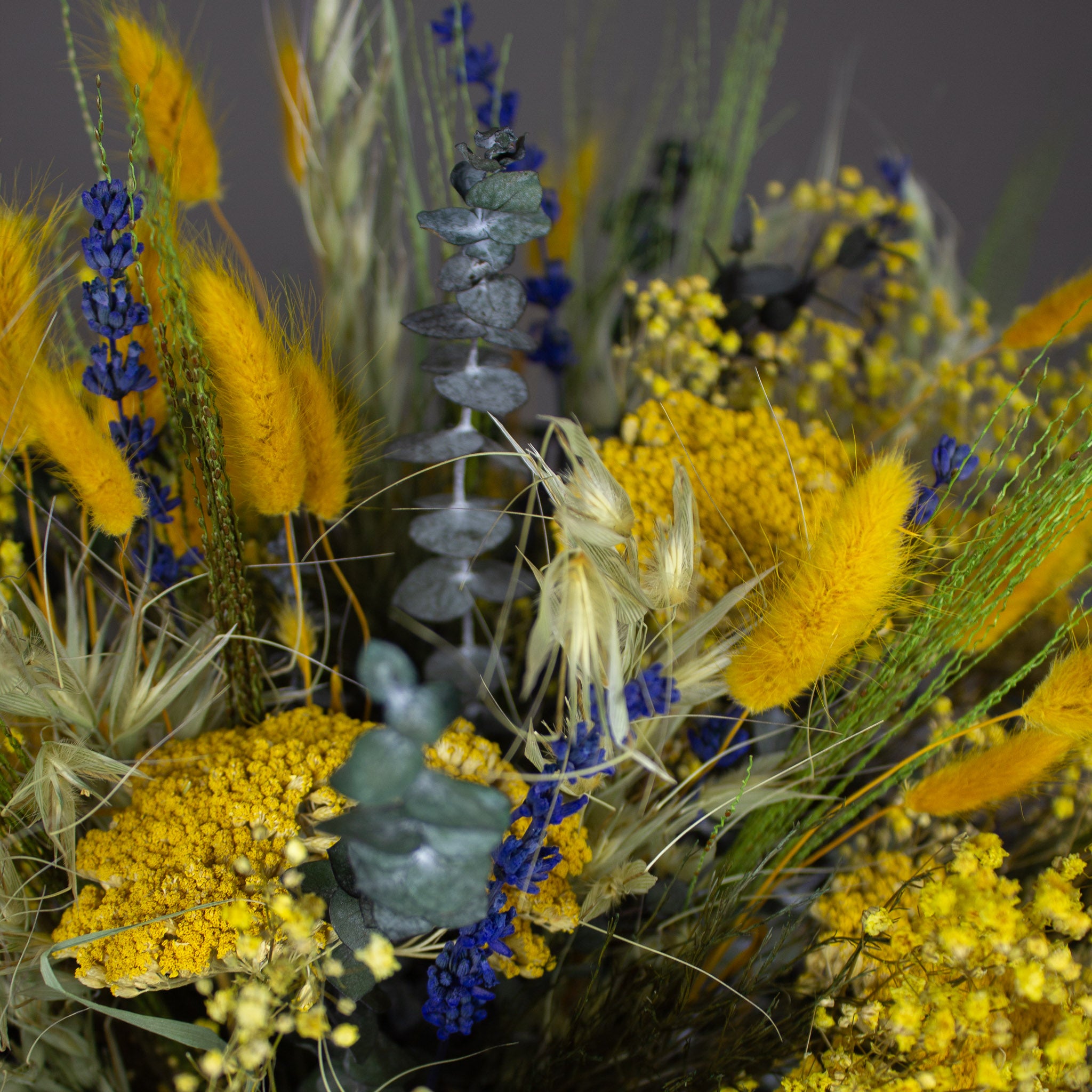 Nærbillede af en gul blomsterbuket med blå accenter.