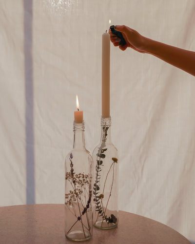 2 vinflasker dekoreret med blomster med lys i